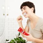 chica lavandose los dientes con dentrifico colgate